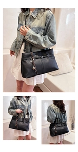 Détail du sac cabas en cuir noir avec boucle argentée et pendentif trèfle décoratif