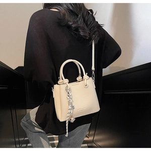 Modern beige litchi leather bucket bag shown as a stylish crossbody on a model outdoors