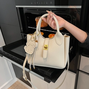 Elegante borsa a secchiello beige in pelle con chiusura dorata e ciondolo