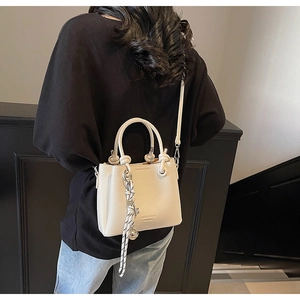 Detail of cream white textured leather bucket bag with rope ornament and branding