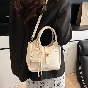 Secchiello in pelle beige con ciondolo a cane indossato su abito floreale