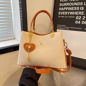 Elegant cream and orange contrast top-handle crossbody bag with heart charm and gold hardware