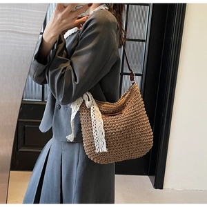 Detail of woven straw crossbody bag with white lace trim and dark brown leather strap