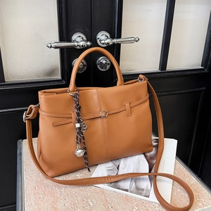 Sac fourre-tout en cuir litchi marron avec breloque B élégante sur marbre