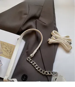 Detail of off-white leather shoulder strap with silver metal chain and spare adjustable strap