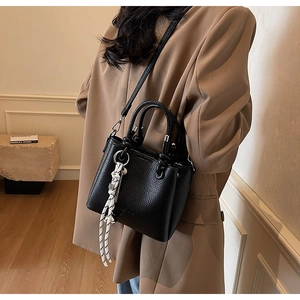Side view of black lychee leather crossbody bag with decorative scarf and shoulder strap