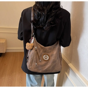 Dettaglio borsa Hobo marrone vintage con logo M, ciondolo orsetto e tracolla regolabile