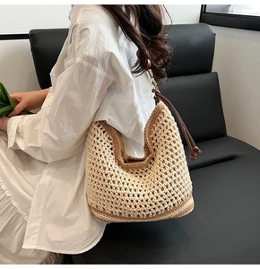 Detail of hand-woven hollow mesh tote bag with leather tassel and brown contrast stripes