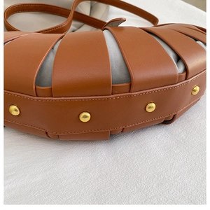 Détail d'un sac à main cage ajouré avec rivets dorés et doublure en tissu bleu
