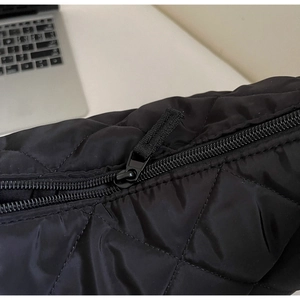 Dettaglio ravvicinato del tessuto in nylon trapuntato nero e della cerniera della borsa
