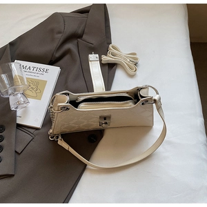 Detail of creamy white quilted underarm bag with silver chain and metal buckle closure