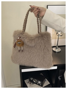 Detail of taupe faux fur handbag with braided handles and cute cartoon doll charm