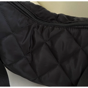 Dettaglio della texture in nylon nero trapuntato e cerniera della grande borsa a tracolla