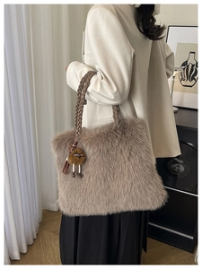 Detail of plush faux fur tote bag in taupe with woven leather handles and cute charm
