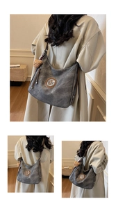 Dettaglio borsa hobo grigia con logo M, texture opaca retrò e ciondolo a forma di orso
