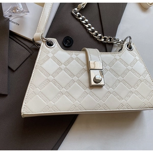 Detail of cream white underarm bag featuring geometric embossing and silver chain link