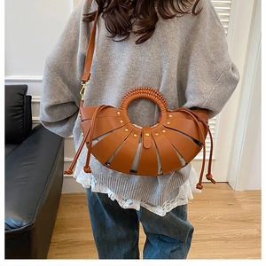 Détail d'un sac à main en cuir marron en forme d'éventail avec rivets dorés et poignée