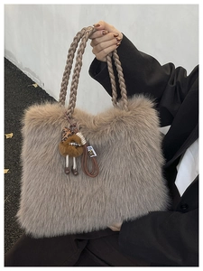Close-up of grey faux fur tote bag with braided handles and small monster charm detail
