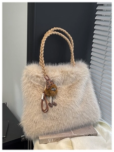 Detailed shot of beige faux fur tote bag with plush charm on a stylish book