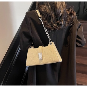 Detail of cream beige underarm bag with geometric embossing and silver chain strap
