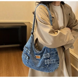 Détail du sac demi-lune en jean bleu vintage avec boucle métallique et sangles rétro