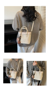 Détail du sac seau en daim crème avec bordure en peluche et texte de mode embossé