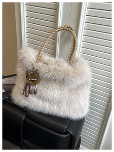 Detail of plush faux fur tote with woven leather handles and owl bag charm accessory