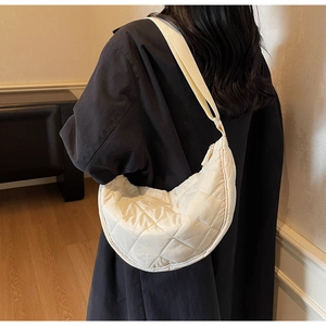 Vista dettagliata di una borsa a tracolla trapuntata crema a mezzaluna su una modella