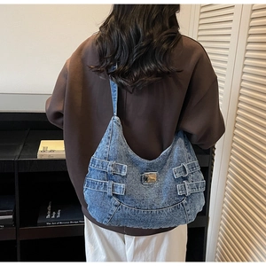 Détail du sac hobo en jean bleu avec sangles décoratives à boucles et plaque en métal