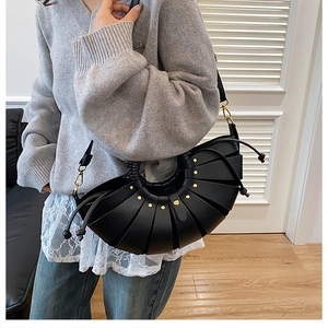 Détail du sac à main noir en forme d'éventail avec rivets dorés et cordon de serrage en cuir