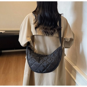 Dettaglio di una borsa a tracolla trapuntata nera a mezzaluna indossata da una persona
