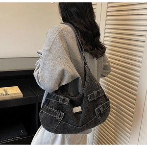 Détails du sac hobo en jean gris délavé vintage avec boucles argentées porté par un modèle