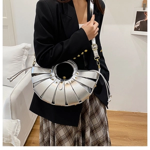 Détail d'un sac à main argenté en forme d'éventail avec rivets dorés et patchwork