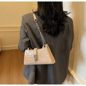 Detail of beige embossed underarm bag with silver chain strap on a grey blazer suit
