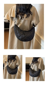 Dettaglio di una borsa a mezzaluna trapuntata nera indossata da una modella in interni