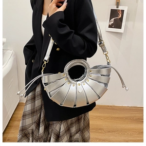 Détail du sac à main plissé argenté avec poignée tressée et rivets dorés