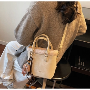 Détail du sac seau en cuir beige avec bordure en peluche et accessoire breloque étoile