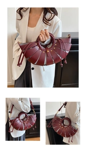 Détail du sac à main en cuir ajouré bordeaux avec rivets dorés et doublure grise