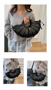Détail du sac croissant plissé noir avec rivets dorés et poignée tressée chic