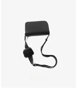 Detail of black textured PU leather crossbody bag with small pouch on adjustable strap