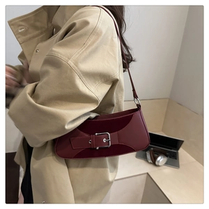Detail showing the burgundy leather texture and silver buckle of the shoulder bag