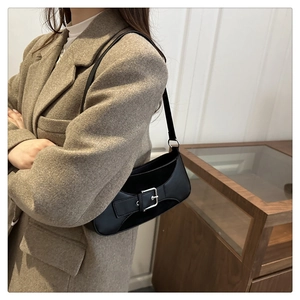 Detail of black leather underarm bag with oversized silver buckle on a model