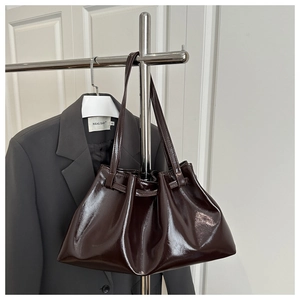 Detail of dark coffee patent leather tote bag featuring glossy finish and pleated closure