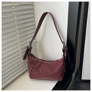 Detail of dark burgundy hobo bag with matte finish and silver hardware on white windowsill