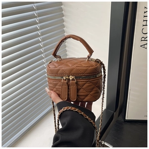 Detailed view of brown quilted leather mini bag with gold chain strap and dual zippers