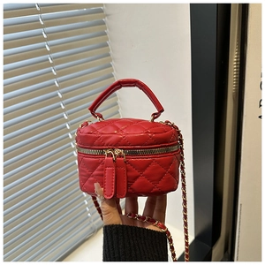 Detail of red quilted vanity case featuring gold chain strap and top handle design