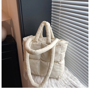 Detail of cream white quilted tote bag showing soft padded texture and dual straps
