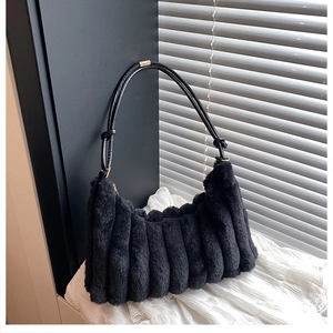 Détail du sac baguette en fausse fourrure noire avec texture et finitions dorées