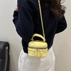 Quilted yellow mini box bag with chain strap and top handle worn by a female model