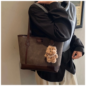 Detail of vintage brown tote bag with leather texture and plush bear pendant
